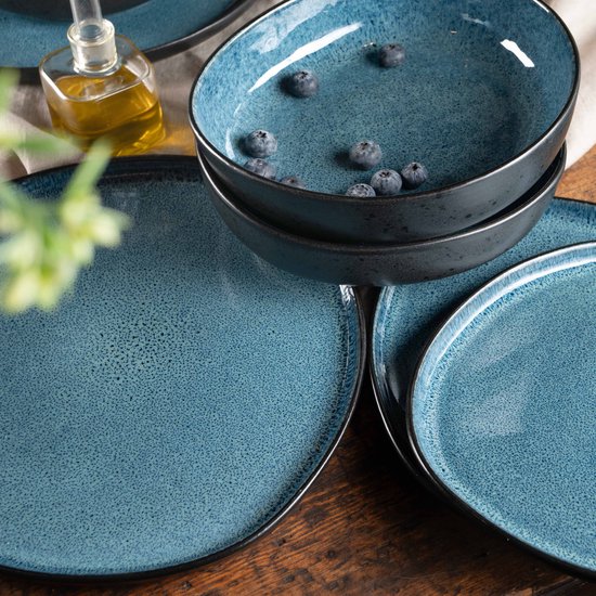 Stapel organische blauwe kommen met stippen en bosbessen, met een rand van olijfolie.