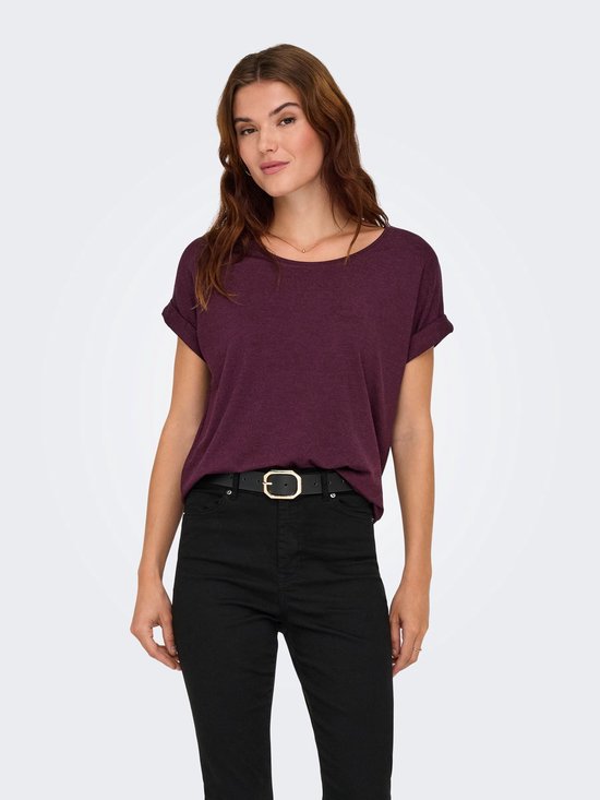 Model draagt bordeauxrood t-shirt met omgeslagen mouwen en zwarte jeans.
