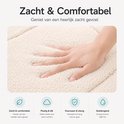 Een hand die zachtjes in de dikke, beige badmat duwt, wat de zachtheid benadrukt.