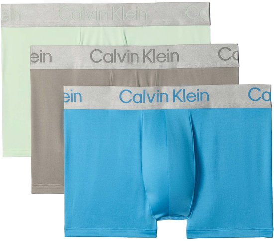 Drie Calvin Klein trunks opgestapeld: lichtgroen, grijs en blauw met logo tailleband.