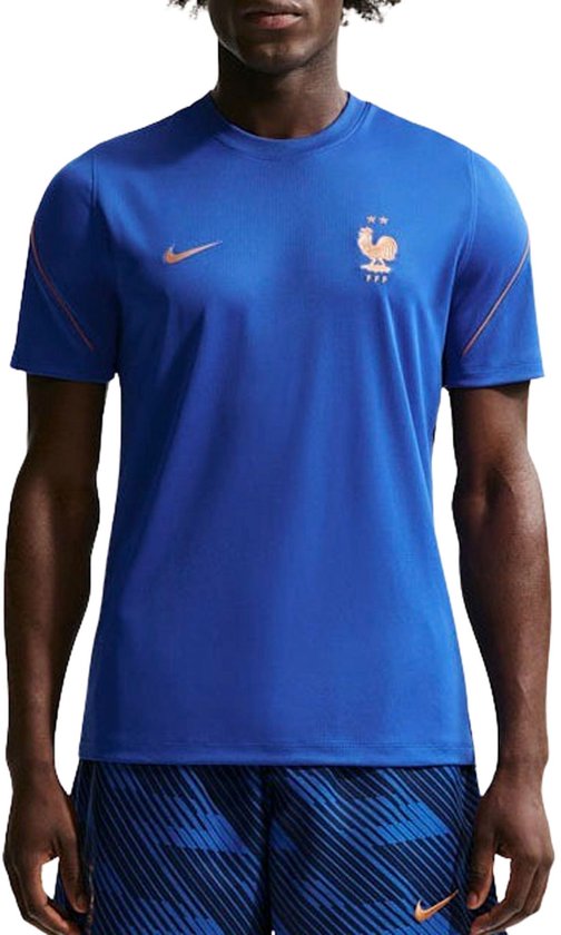 Man in een blauw Frankrijk voetbalshirt met oranje accenten op de schouders en borst. Oranje FFF-logo linksboven.