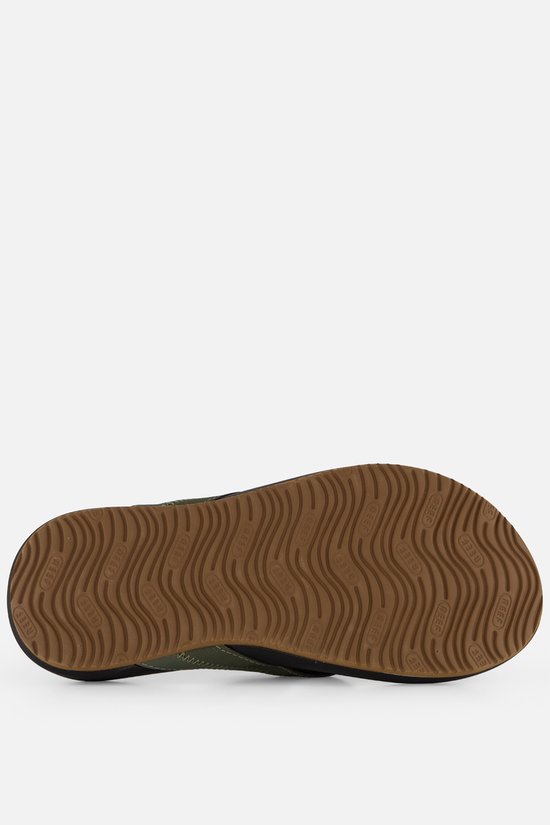 Bruine rubberen zool van een zwarte Reef slipper met olijfgroene band. De zool heeft een golvend profiel.