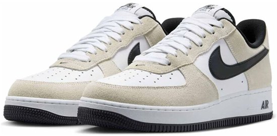 Paar witte sneakers met beige suède overlays, zwart Swoosh-logo en "AIR" op de zool.
