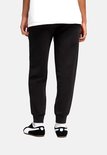 Achterkant van model in zwarte Puma joggingbroek met elastische tailleband.
