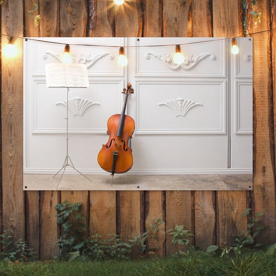 Tuinposter 180x120 cm - Tuindecoratie Een cello tegen een witte muur - Poster voor in de tuin - Buiten decoratie - Schutting tuinschilderij - Tuindoek muurdecoratie - Wanddecoratie balkondoek