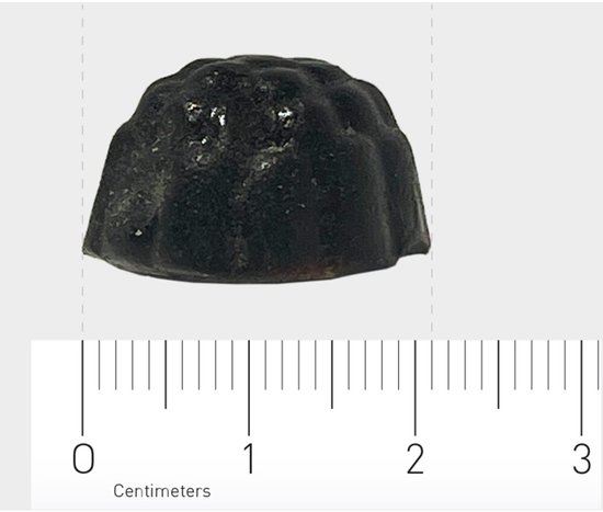 Zwarte, ronde gummie met een bloemachtig patroon, gemeten met een centimeter schaal.