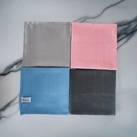 Quatre lingettes microfibres carrées grises, roses, bleues et anthracite, chacune avec un motif à carreaux, sur un fond marbré.