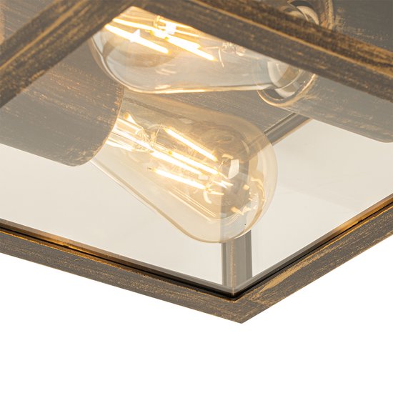 Close-up van een vierkante buitenlamp met glazen zijkanten en een verweerd gouden frame, met zichtbare lampen.