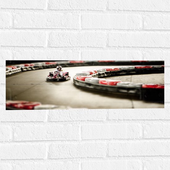 WallClassics - Muursticker - Karter op Indoor Kartbaan - 60x20 cm Foto op Muursticker