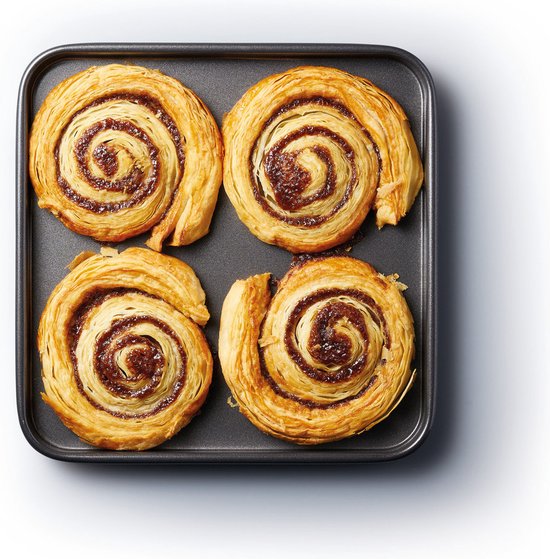Vier kaneelbroodjes in een vierkante bakplaat.