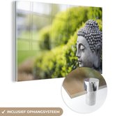 MuchoWow® Glasschilderij 150x100 cm - Schilderij acrylglas - Standbeeld van Boeddha in een tuin - Foto op glas - Schilderijen