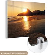 MuchoWow® Glasschilderij 160x120 cm - Schilderij acrylglas - De zon verdwijnt achter de berg bij het Ipanema strand in Brazilië - Foto op glas - Schilderijen