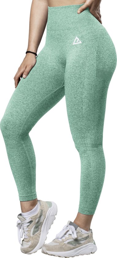 Vrouw in turquoise sportlegging met een witte logo-print op de heup, staand met de hand in de zij.