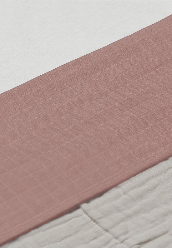 Detail van het wieglaken met een roze band en beige gekreukelde stof.