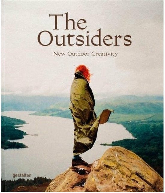 Boekomslag 'The Outsiders: New Outdoor Creativity' met een persoon op een rots met uitzicht op een meer.
