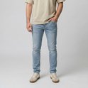 Model draagt lichtblauwe jeans, beige T-shirt en sneakers.