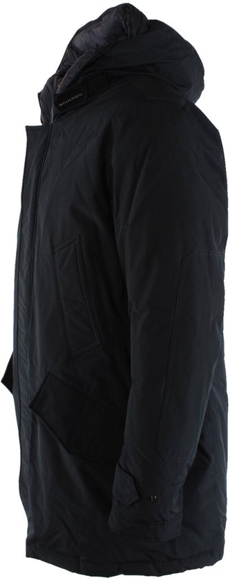 Zwarte Woolrich jas met capuchon, van opzij gezien. Met twee steekzakken en knoopsluiting aan de onderkant van de mouwen.