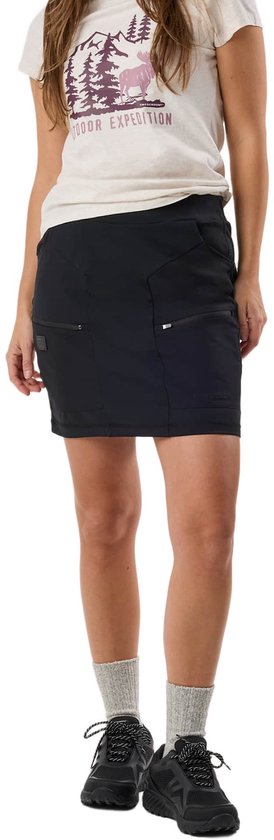 Vrouw in een witte T-shirt met opdruk van een eland en "OUTDOOR EXPEDITION", een zwarte outdoor rok, grijze sokken en zwarte wandelschoenen.