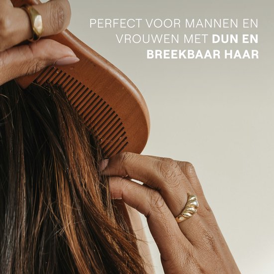 Vrouw met lange bruine haren, die haar haar borstelt met een houten kam. Ze draagt gouden ringen.