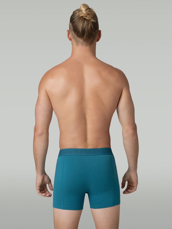 Achterkant van een man in een blauwgroene Muchachomalo boxershort. Logo zichtbaar op de tailleband.
