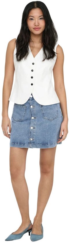 Model in een witte, mouwloze top met V-hals en zwarte knopen, en een lichtblauwe denim minirok met knoopsluiting en voorzakken.