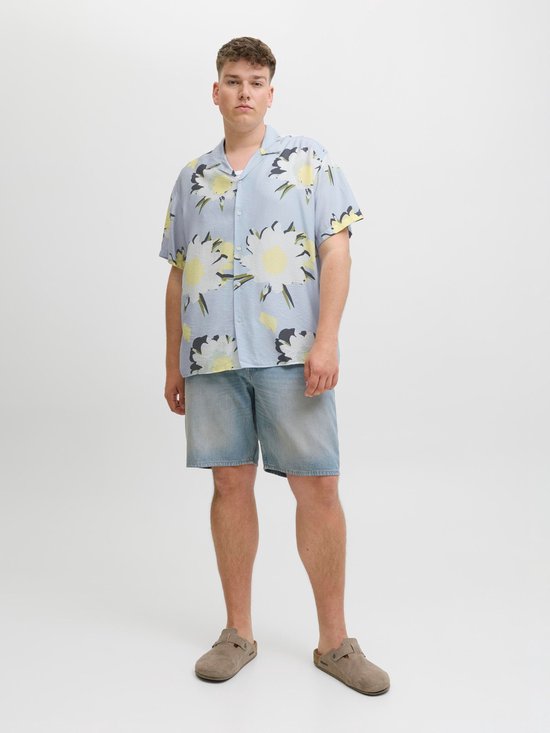 Man in lichtblauw kort hemd met bloemenprint en jeans.
