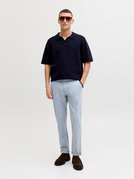 Man met donkerblauw poloshirt en lichtblauwe pantalon met ruitpatroon en omgeslagen pijpen.
