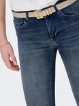 Detail van de tailleband van een blauwe skinny jeans met een beige riem.