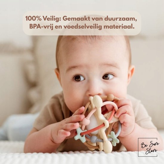 Baby ligt op zijn buik en bijt op de pastelkleurige rammelaar en bijtring.
