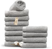 Stapel grijze handdoeken op een zwarte achtergrond, met een 'Miss Towels' label en katoenbollen.