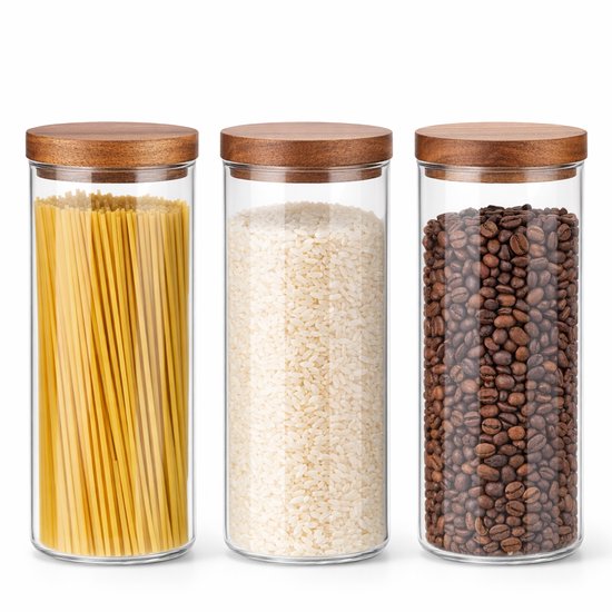 Drie glazen voorraadpotten met walnoothouten deksels, gevuld met spaghetti, rijst en koffiebonen.