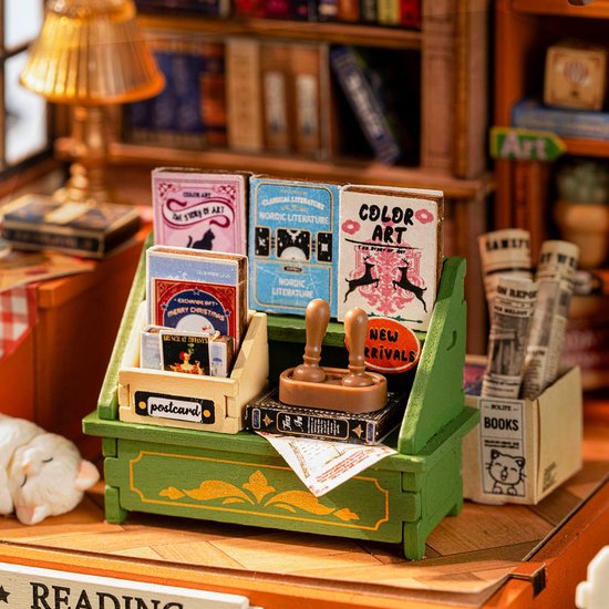 Close-up van de miniatuur boekenwinkel balie met boeken, ansichtkaarten, een stempel en kranten.