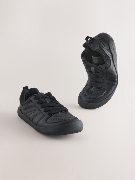 Zwarte leren veter-sneakers, één sneaker staat rechtop, de andere ligt plat, met perforaties op de neus.
