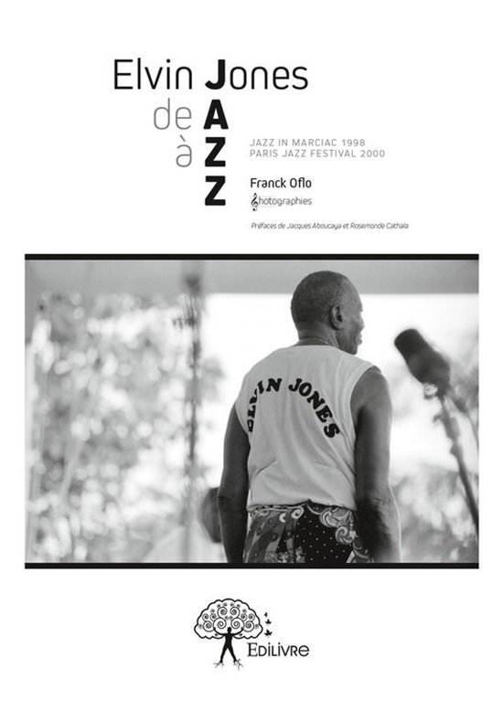 Elvin Jones in een wit T-shirt met tekst 'ELVIN JONES' op de rug, kijkend naar rechts.