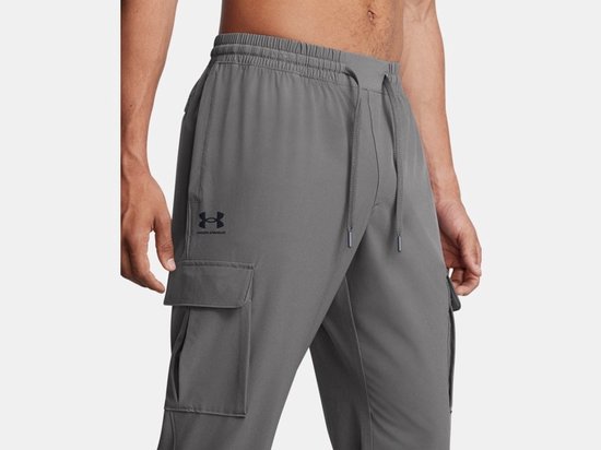 Close-up van grijze cargo trainingsbroek met Under Armour logo.