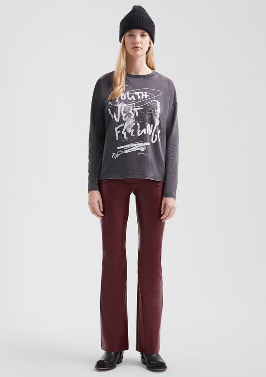 Model met zwarte muts draagt een grijs T-shirt met 'YOUTH WEST FEELING' tekst, een bordeaux leren broek en zwarte laarzen.