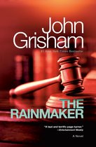 Boek kaft The Rainmaker van John Grisham met een houten hamer en blok op een houten tafel.
