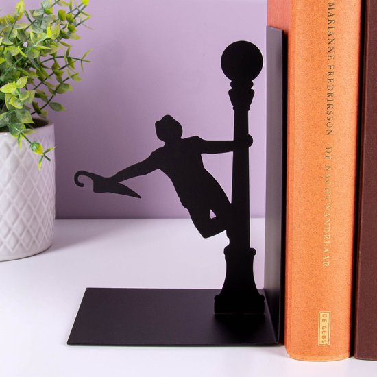 Zwarte metalen boekensteun met zingende man en paraplu, naast oranje en bruine boeken.