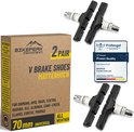 Twee paar zwarte V-brake remblokken met "WEAR LINE" opdruk en een metalen houder. Naast de remblokken staat een doos met kwaliteitskeurmerk "Prüfengel Passed Proven Quality".