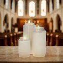 Drie brandende witte kaarsen op een marmeren tafel met kerkinterieur op de achtergrond.