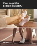 Lichtroze enkelsokken op een vrouw bij een tafel en een sportvrouw bij een atletiekbaan.