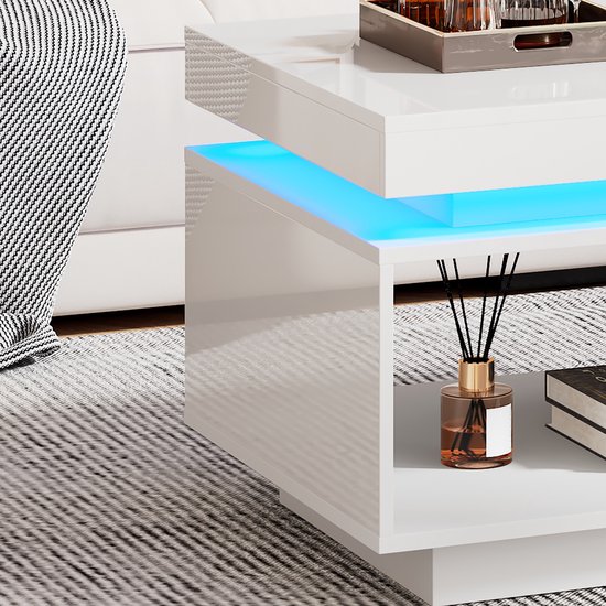 Detail van de witte hoogglans salontafel met blauwe LED-verlichting, een open vak met decoratie en een grijs gestreept tapijt.