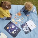 Twee kinderen spelen met houten planeten en posters in de tuin