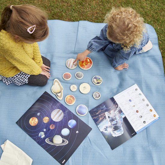Twee kinderen spelen met houten planeten en posters in de tuin