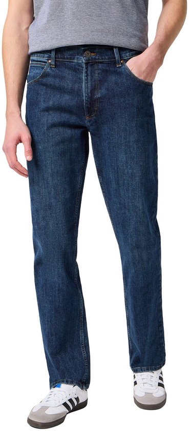 Man met een donkerblauwe jeans en een grijs shirt, witte sneakers.