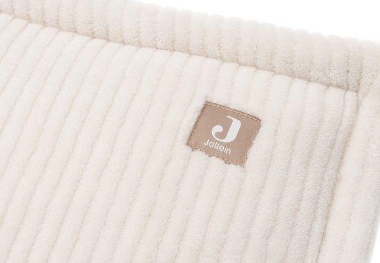 Close-up van het crème, ribbelstof van de Jollein ledikantbumper met label.