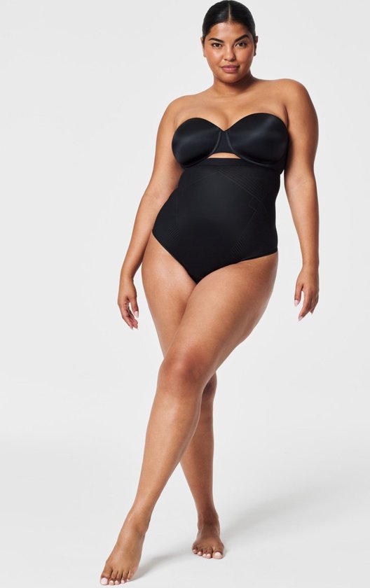 Mannequin vu de face, debout, portant une culotte taille haute noire avec un dos string.