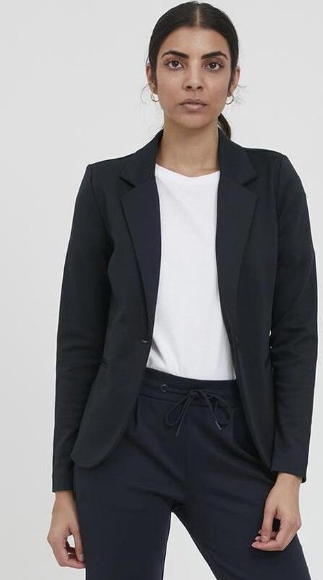 Model in een donkerblauwe blazer met een enkele knoop en een witte top.