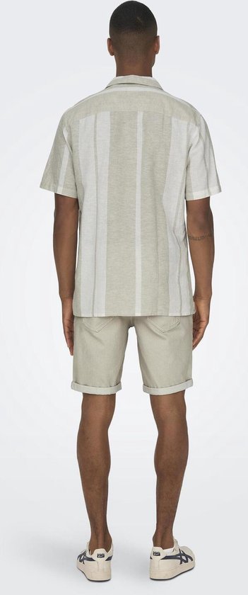 Man van achteren, draagt beige kortarmig gestreept overhemd en beige shorts.