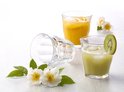 Trois verres Duralex, dont deux remplis de jus orange et vert, et un verre renversé.